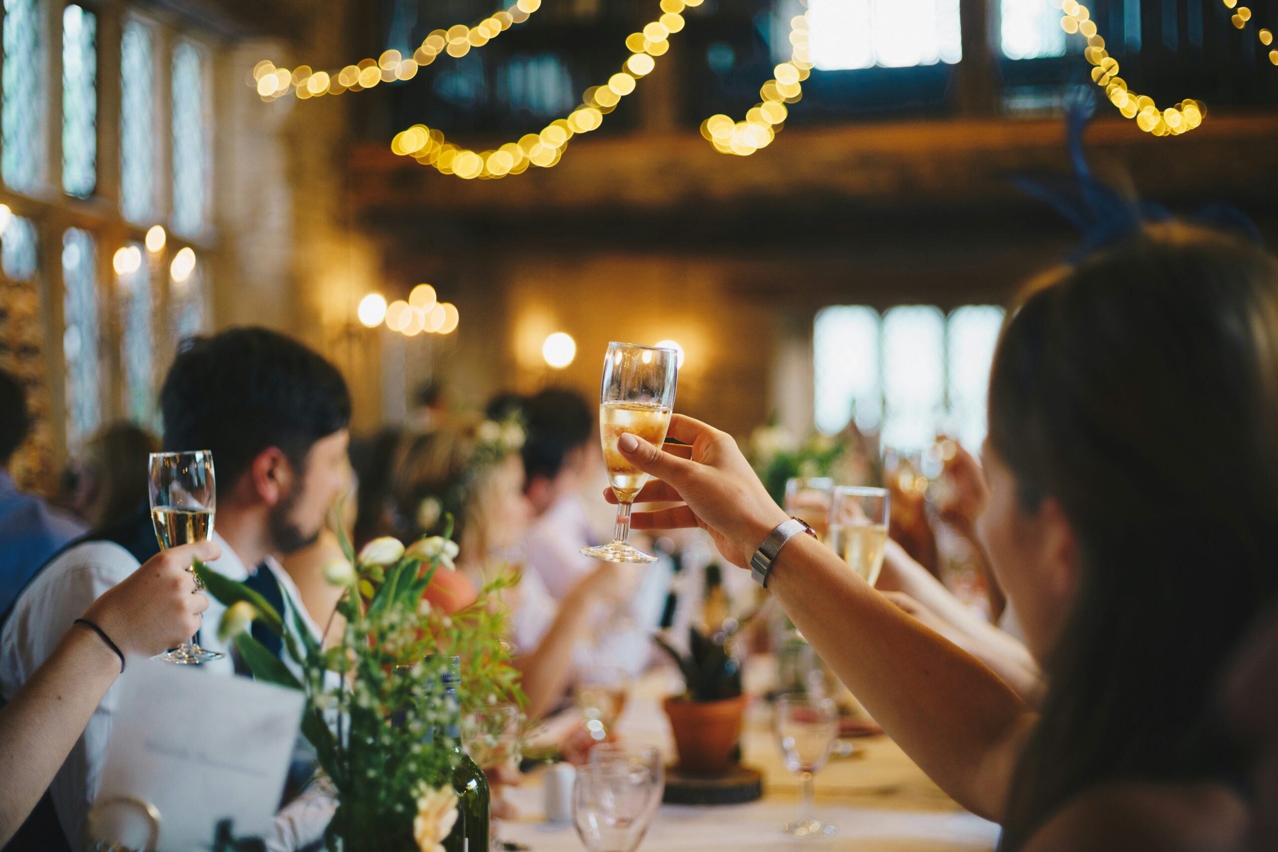 People raising champagne glasses in a warmly lit venue.