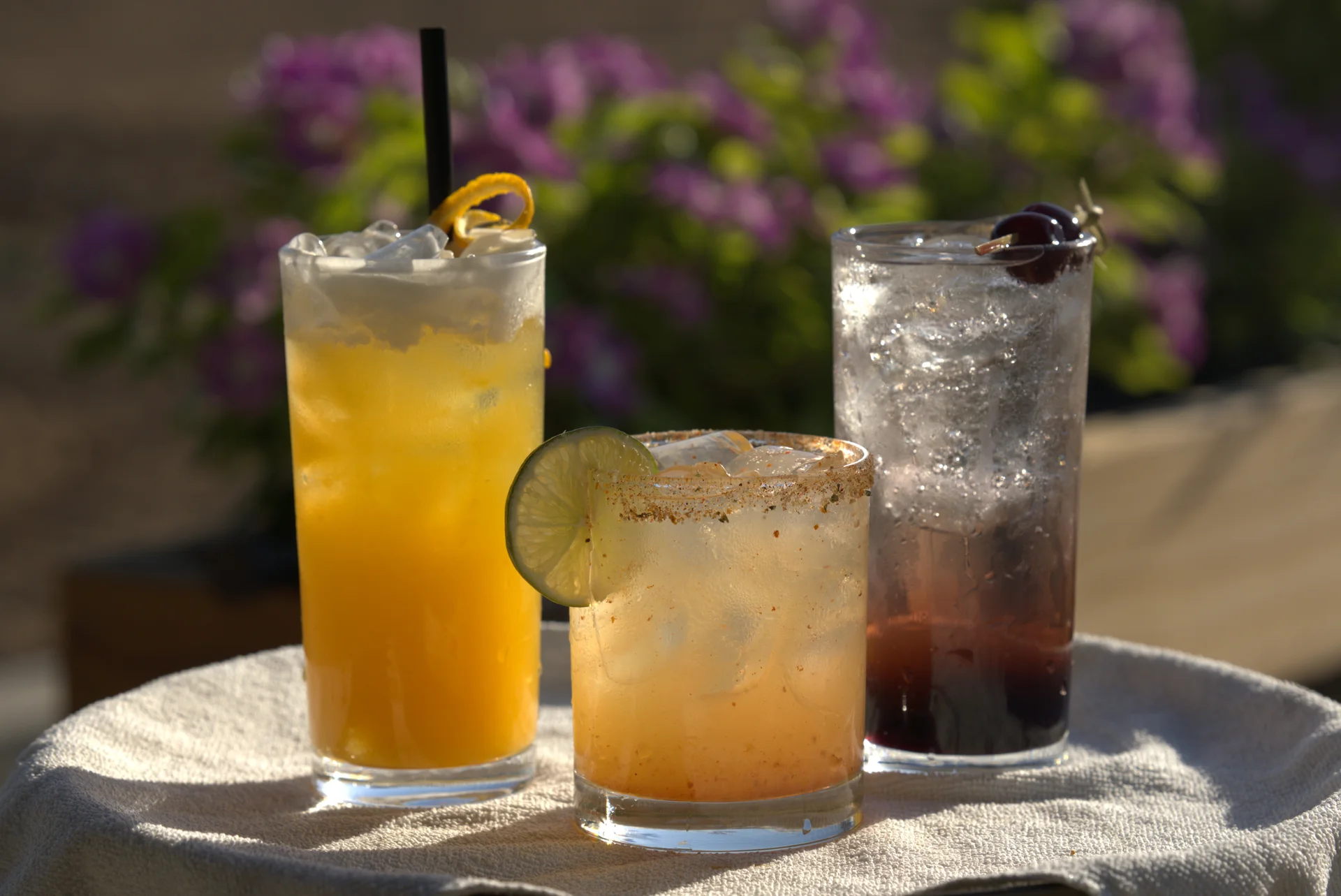 Three colorful cocktails in glasses on a table with a white cloth
